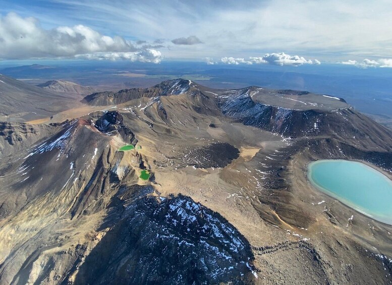A volcanic landscape with a crater lake and snow patches. 3