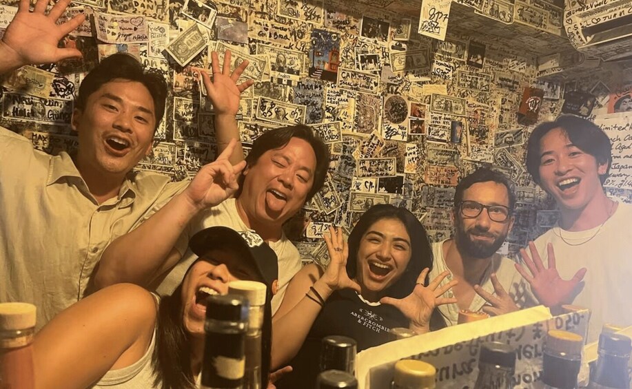 A group of people posing in front of a wall covered with various stickers and notes. 1