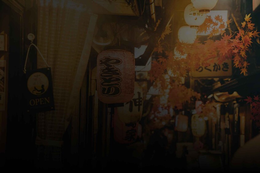 A narrow street with traditional Japanese signage and autumn foliage. 5