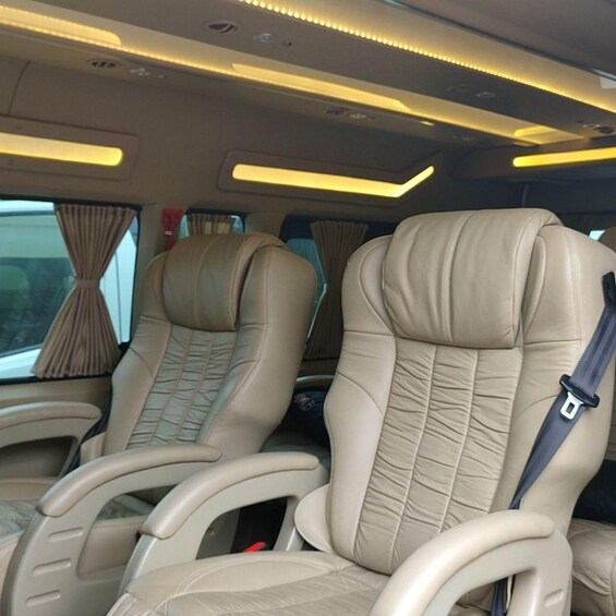 A vehicle interior with beige leather seats, headrests, and a seatbelt. 3