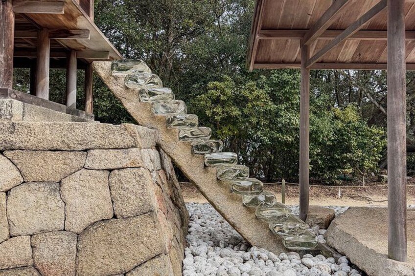 A stone staircase with glass steps leading up to a wooden structure. 2