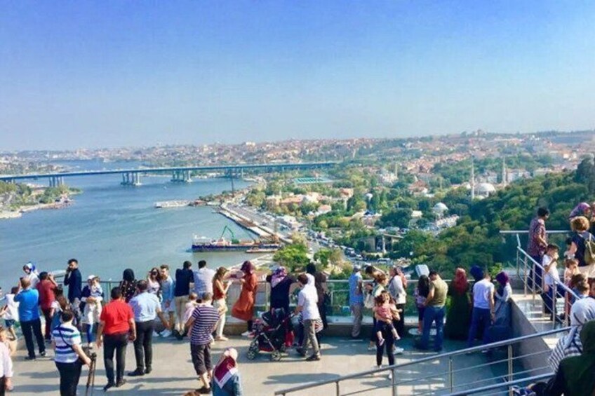 A crowded riverside promenade with a bridge in the background. 3