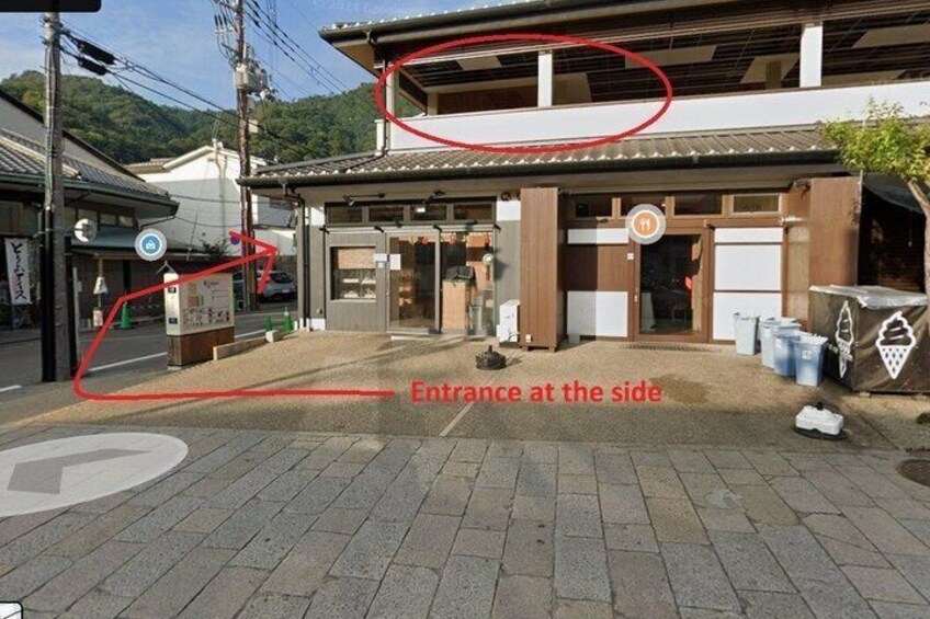 A traditional Japanese building with a tiled roof, a wooden entrance, and a paved ground with a directional arrow. 3