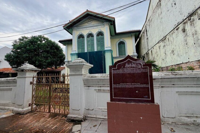 A traditional building with a gate, a tree, and a signboard. 5