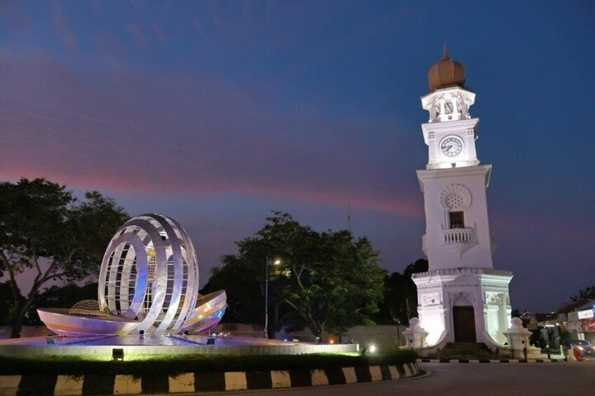 A modern sculpture and a traditional tower at dusk. 3