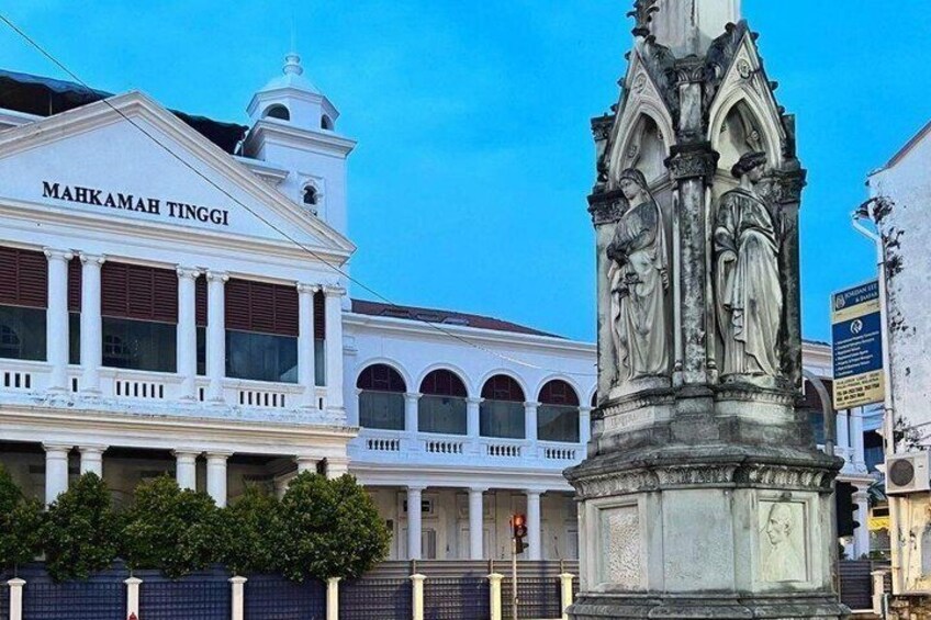 A white building with columns and a statue in front. 2
