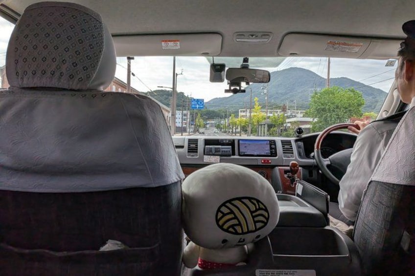 A vehicle interior with a steering wheel, dashboard, and a view of a mountainous landscape through the windshield. 2