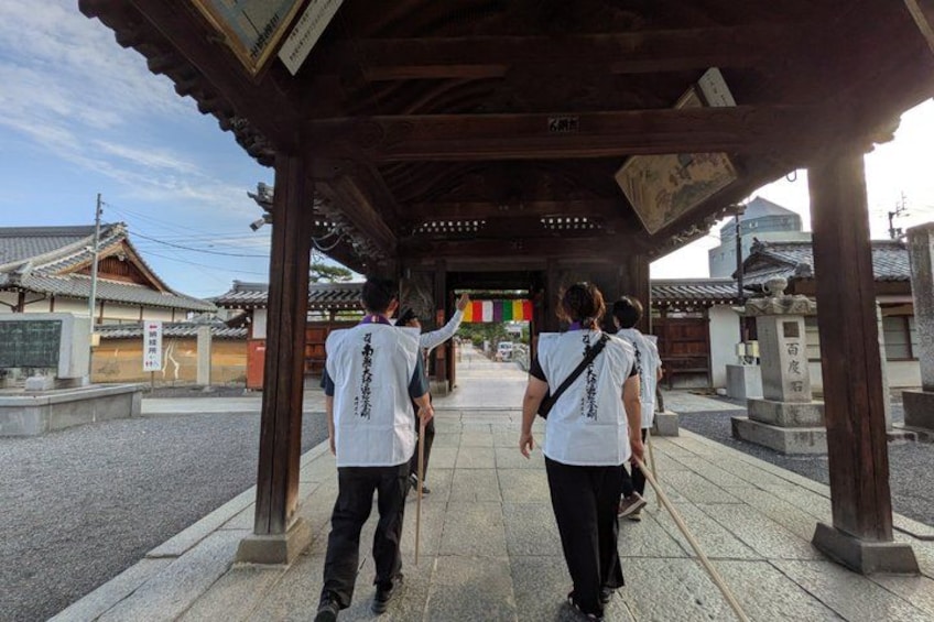 A group of people walking under a traditional wooden structure with a tiled roof. 4