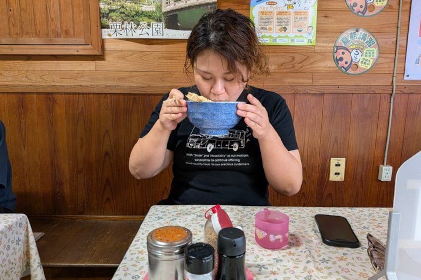 A person eating at a table with a bowl, a phone, and a pink cup. 5