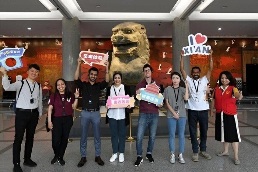A group of people holding signs and posing in front of a large lion statue. 3