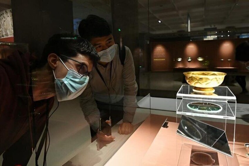 Two people examining an artifact in a museum display case. 2
