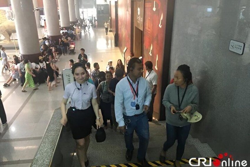 A crowded indoor walkway with people walking and standing. 5