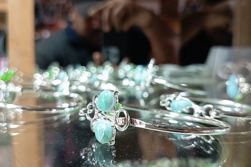 A display of jewelry with a focus on a ring with a large green gemstone. 1