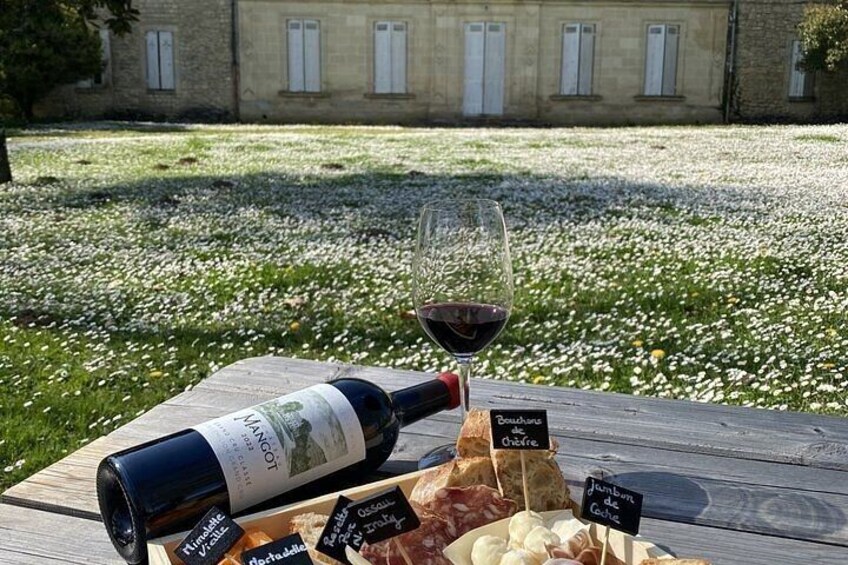 A picnic setup with a bottle of wine, glasses, and cheese on a wooden table. 1