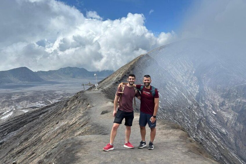 Two people standing on a rocky path with a mountainous landscape in the background. 3