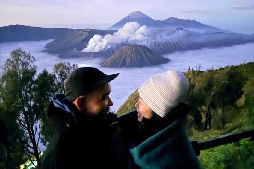 Two people observing a volcanic eruption with smoke and clouds. 2