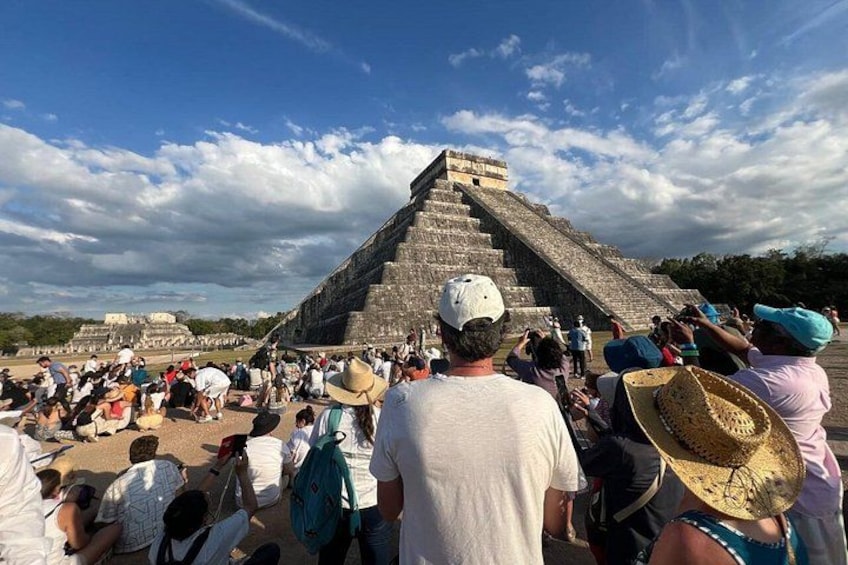 A large pyramid with tourists gathered around it. 4