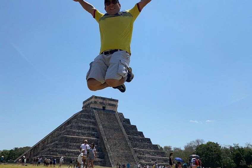 A person jumping in front of a large pyramid structure. 1