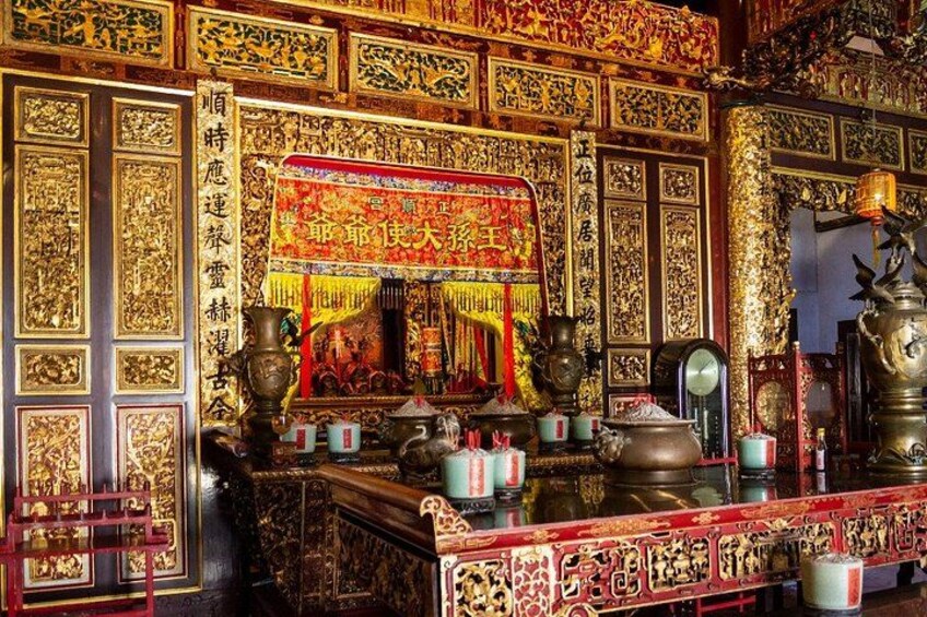 An ornate shrine with intricate golden decorations, a central altar, and various ritual items. 3