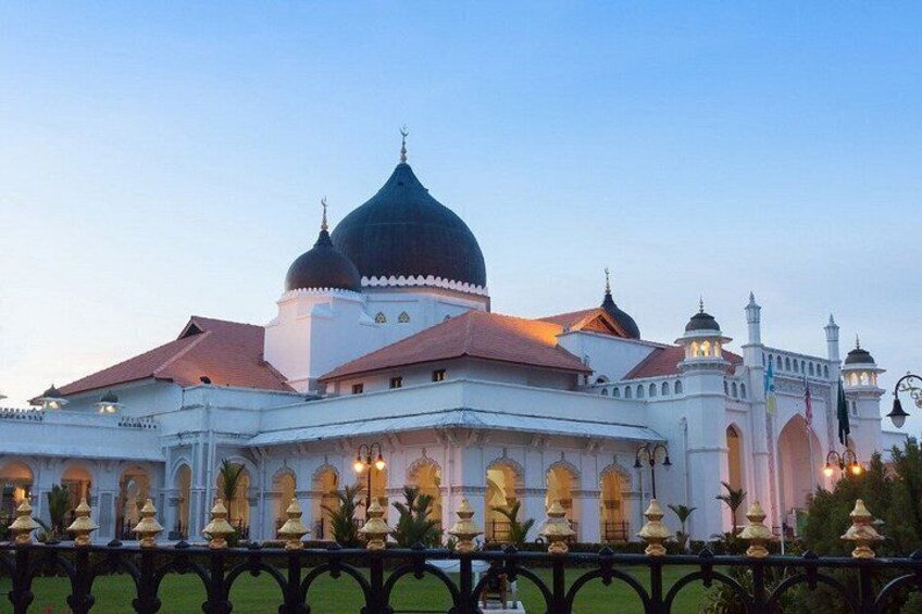 A large white building with a prominent black dome, arched windows, and a fence with golden statues. 4