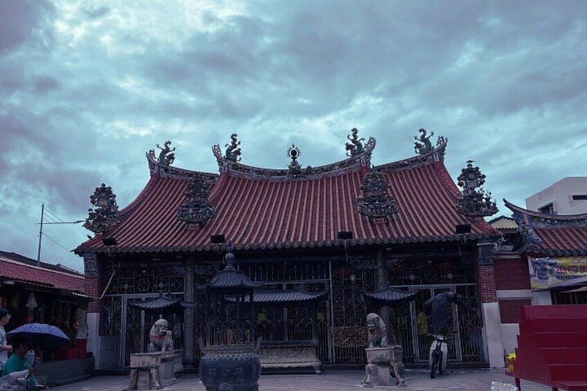 A traditional Chinese building with ornate red-tiled roofs and statues. 2
