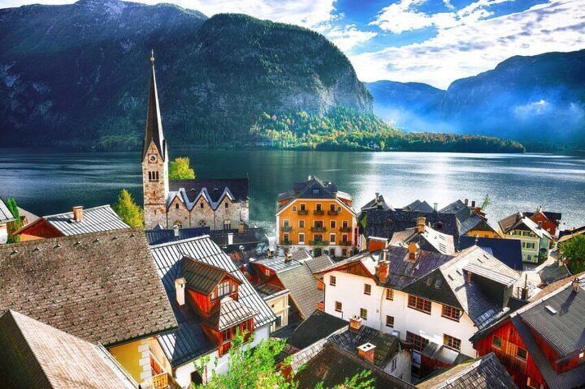 A lakeside town with a church, colorful buildings, and mountains in the background. 4