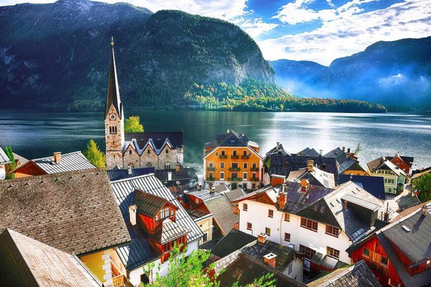 A lakeside town with a church, colorful buildings, and mountains in the background. 4