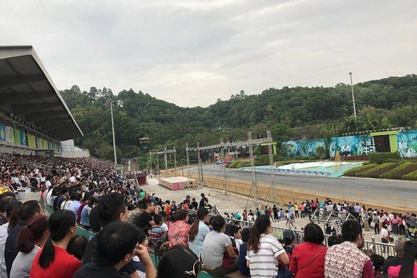 Una multitud en un evento deportivo, un escenario y un paisaje montañoso de fondo. 3