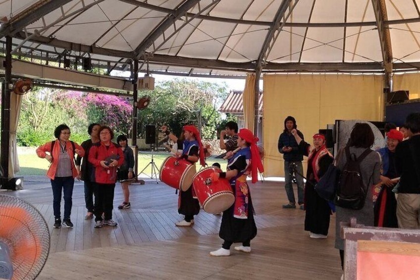 A group of people performing on a stage with musical instruments, under a tent. 5