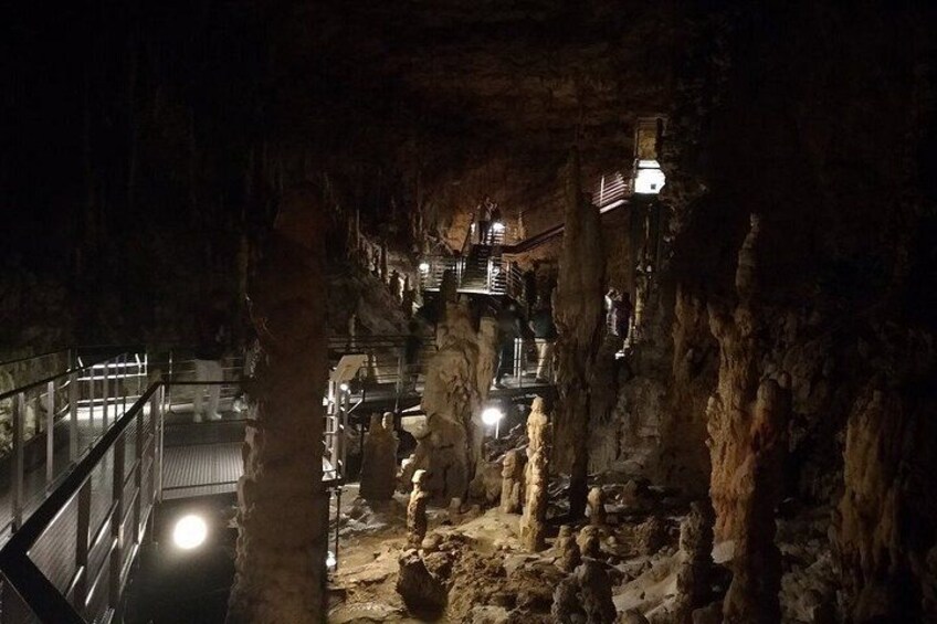 A cave interior with a staircase, rock formations, and a railing. 4