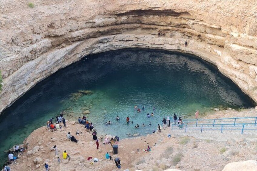 A natural rock formation with a pool of water and people swimming and standing around. 4