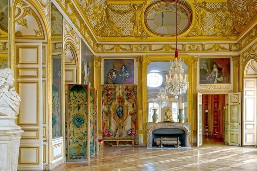 An ornate room with gold accents, a fireplace, and a chandelier. 2