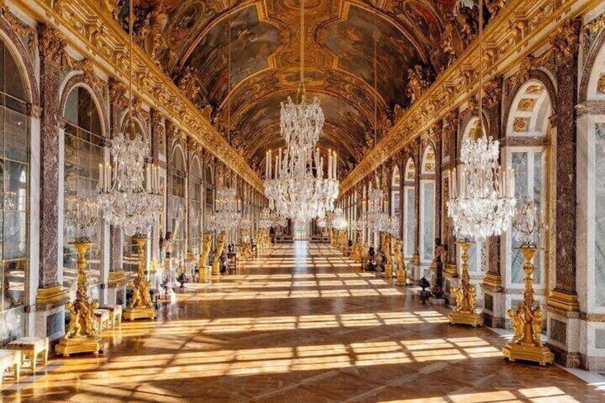 An opulent hall with a long corridor, ornate chandeliers, and golden statues. 5