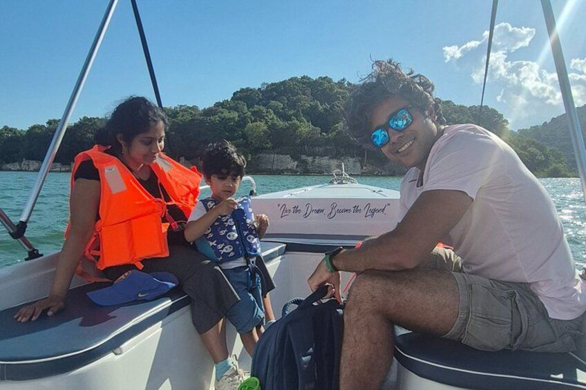 Three people on a boat with a rocky coastline in the background. 3