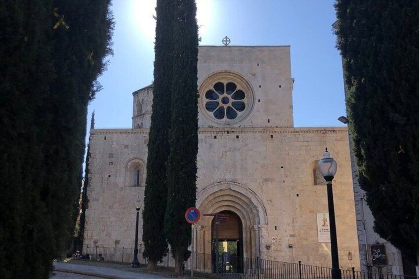 A historic building with a large arched entrance, a circular window, and a bell tower. 5