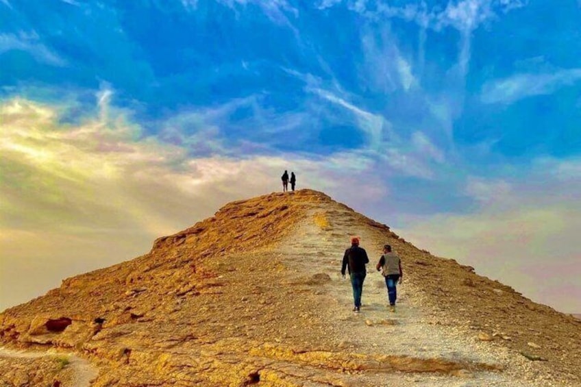 A rocky hill with two people walking towards the summit. 4