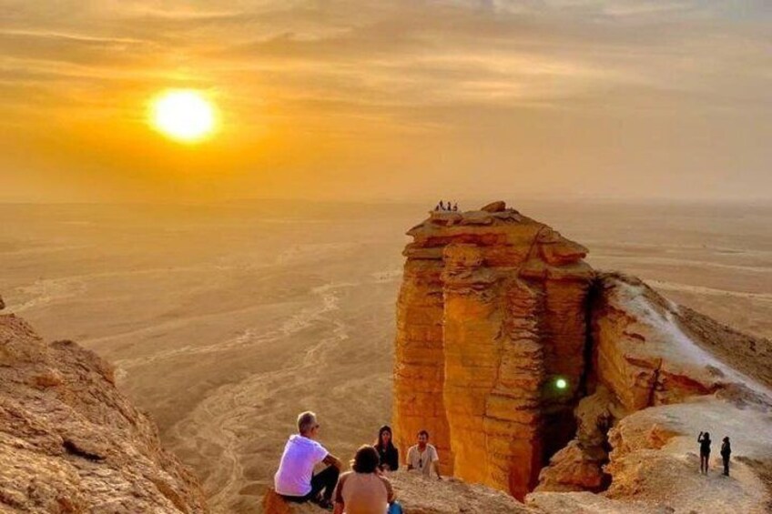 A rock formation at sunset with people observing it. 5