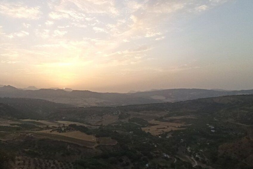 A valley with scattered buildings, a river, and distant mountains under a clear sky. 2