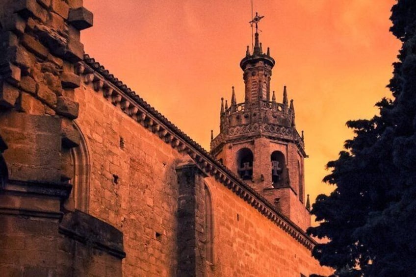 A stone building with a tower, arched windows, and a weather vane. 3