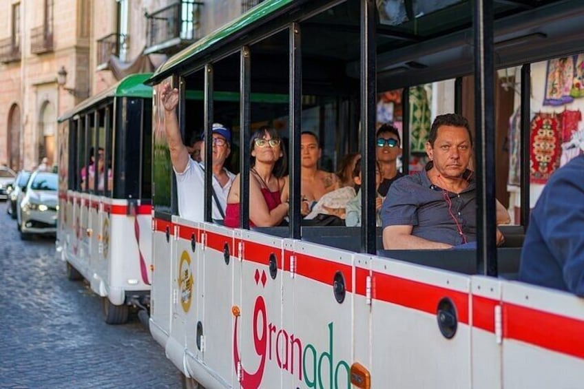 A tram with passengers, a cobblestone street, and buildings in the background. 4