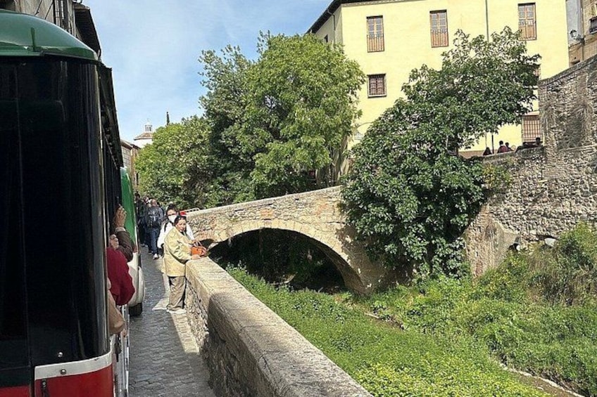 A stone bridge, a red bus, and a yellow building. 5