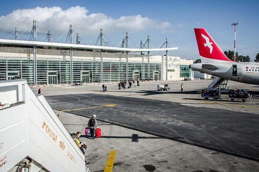 An airport tarmac with a Swiss flag airplane, a terminal building, and ground service vehicles. 1