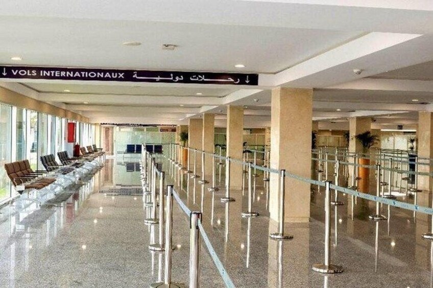 A spacious airport terminal with a clear walkway, seating area, and a sign indicating the international departure area. 3