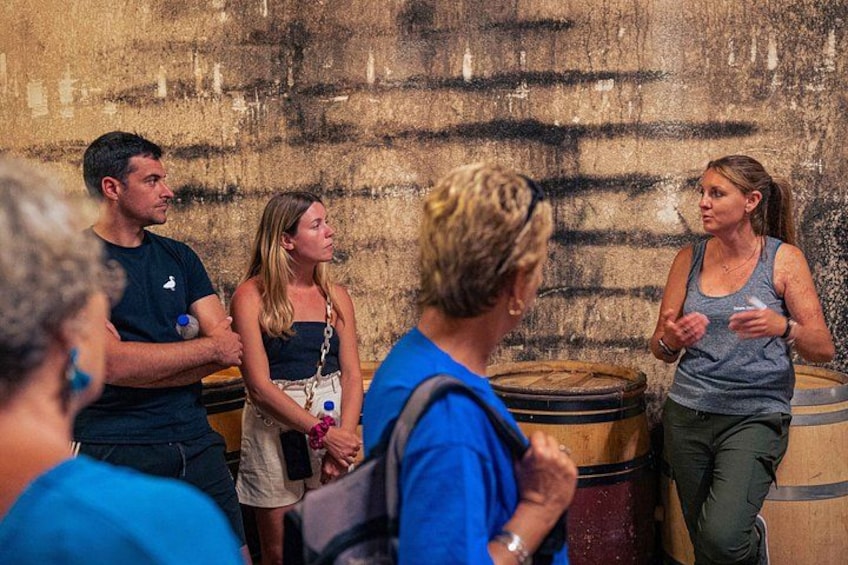 A group of people in a rustic setting with wooden barrels and a textured wall. 2