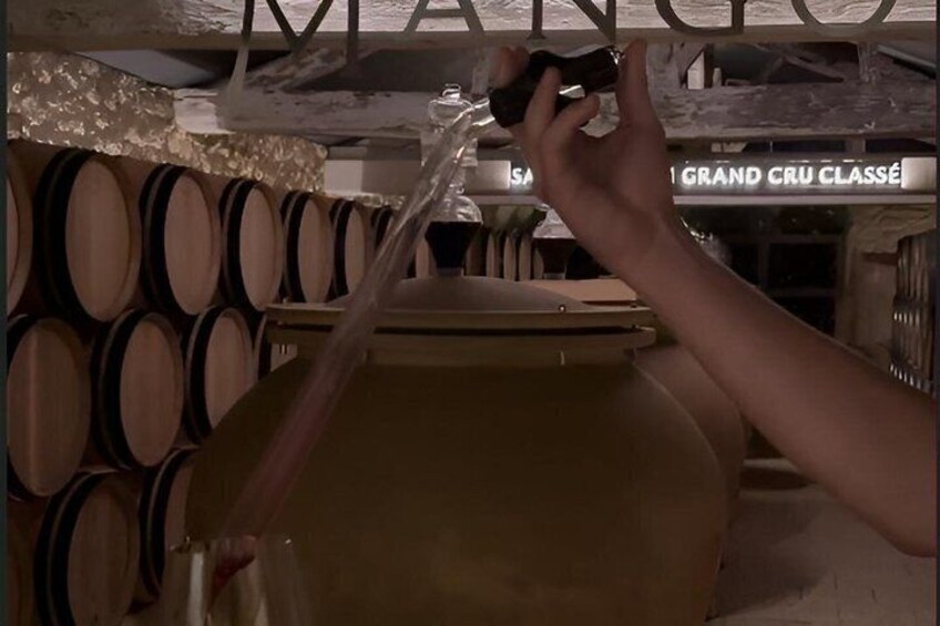 A hand pouring liquid from a bottle into a large container. 5