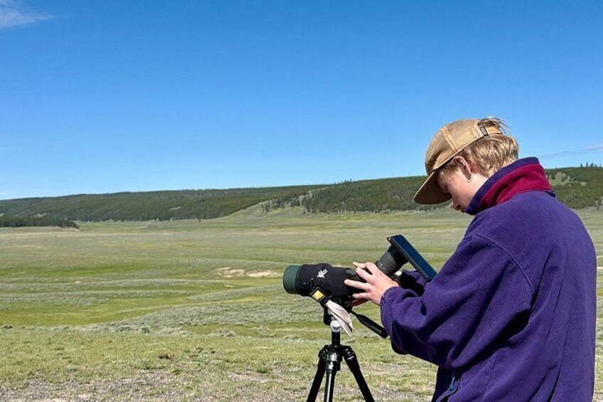 A person using a telescope in an open field with a clear sky. 3