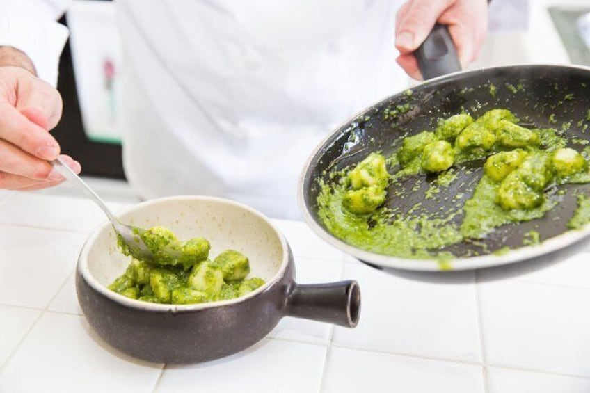A person cooking with a pan and a bowl of green sauce. 5