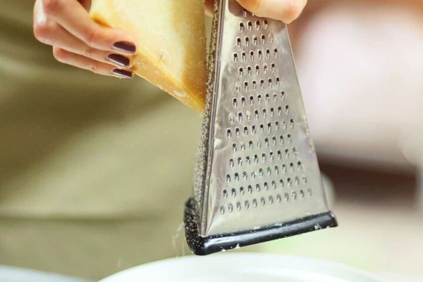 A person grating cheese with a metal grater. 3