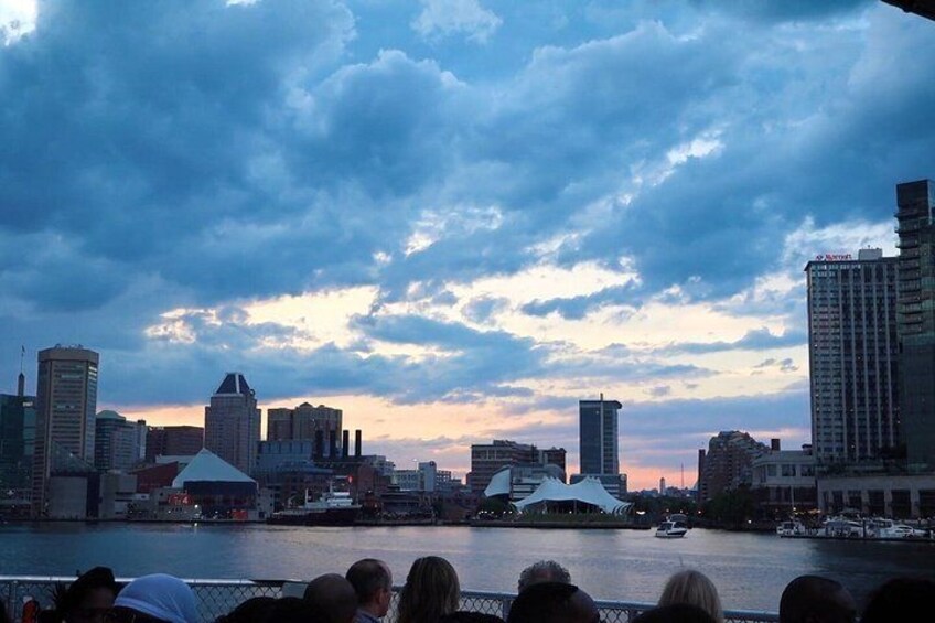A city skyline at dusk with a river in the foreground and a crowd of people. 4