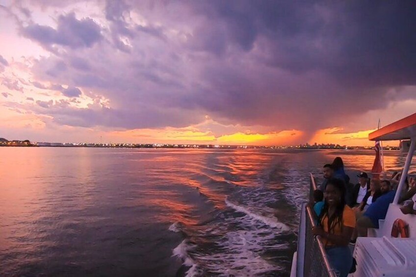 A sunset over a body of water with a boat and people on it. 1